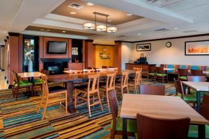 Fairfield Inn & Suites Verona في فيرونا: غرفة طعام بها طاولات وكراسي وتلفزيون