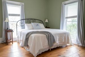 a bedroom with a white bed with two windows at Athenaeum Hotel in Chautauqua