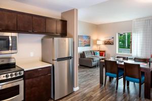 a kitchen with a refrigerator and a table with chairs at TownePlace Suites by Marriott Fort Myers Estero in Estero