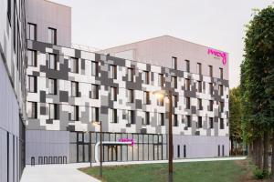 Moxy Paris Val d'Europe في مونتِفري: مبنى عليه لوحه ورديه