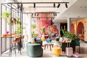 a lobby with couches and tables and plants at Moxy Paris Val d'Europe in Montévrain