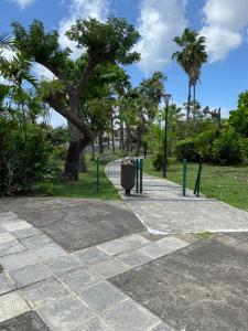 a park with a trash can next to a tree at Chez Marc in Les Abymes