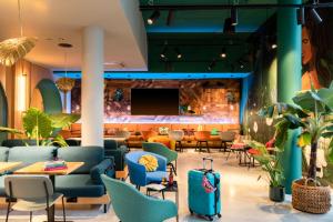 a lobby of a restaurant with blue chairs and tables at Moxy Paris Val d'Europe in Montévrain