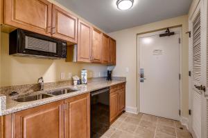 a kitchen with wooden cabinets and a sink and a microwave at Marina Inn Grande Dunes Unit 7-301A in Myrtle Beach