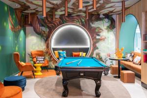 a room with a pool table and a mirror at Moxy Paris Val d'Europe in Montévrain