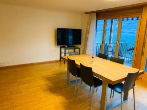 een eetkamer met een tafel en stoelen en een televisie bij Lake View Residence -16 in Niederried