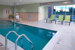 - une piscine avec des chaises vertes dans un bâtiment dans l'établissement SpringHill Suites by Marriott Kansas City Lenexa/City Center, à Lenexa