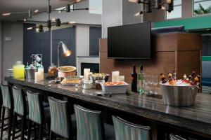 un bar con sedie e cibo e una TV a schermo piatto di Residence Inn by Marriott New Orleans Elmwood a Elmwood