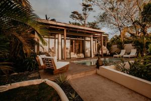 une maison avec une piscine, des chaises et une maison dans l'établissement Sansara Surf Yoga & Resort, à Cambutal