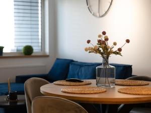 a table with plates and a vase of flowers on it at Apartament Termalny in Uniejow