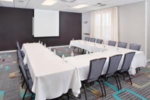 a conference room with white tables and chairs and a screen at Residence Inn Chicago O'Hare in Rosemont
