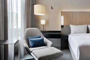 um quarto com uma cama e uma cadeira com uma almofada azul em Courtyard by Marriott Freiburg em Friburgo em Brisgóvia