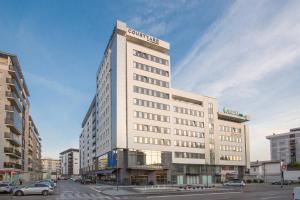 ein großes weißes Gebäude in einer Stadtstraße mit Autos in der Unterkunft Courtyard by Marriott Banja Luka in Banja Luka