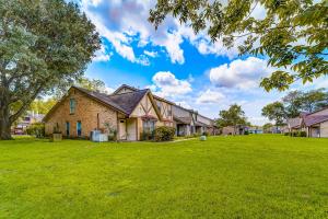 a house on a lawn with a large yard at Country Village Condo in Humble