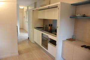 une petite cuisine avec des placards blancs et un couloir dans l'établissement Lovely Apartment in Lignano Sabbiadoro, à Lignano Sabbiadoro