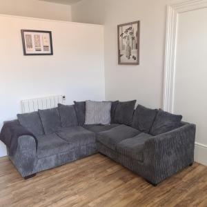a gray couch in a living room with a wooden floor at Cozy apartment in Burton town centre in Burton upon Trent