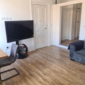 a living room with a flat screen tv and a chair at Cozy apartment in Burton town centre in Burton upon Trent