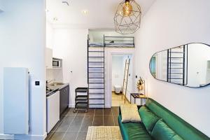 a living room with a green couch and a kitchen at Lyon Cité-Studio Bellevue Caluire in Caluire-et-Cuire