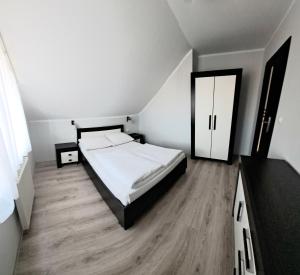 a bedroom with a white bed and a wooden floor at D.W. JULIA in Władysławowo