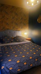 a bedroom with a bed with a blue and orange comforter at La P'tite Arrageoise in Arras