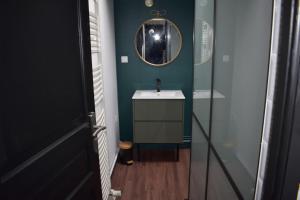 een badkamer met een wastafel en een spiegel aan de muur bij La P'tite Arrageoise in Arras