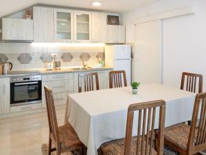 eine Küche mit einem Tisch und Stühlen sowie eine Küche mit weißen Schränken in der Unterkunft My Parents Guest House in Petrovec