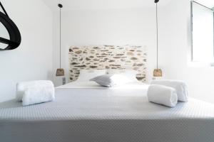 a white bedroom with a large bed with white sheets at Santa Marina Syros in Liaropá