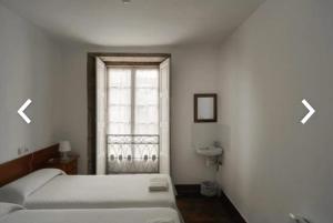 a bedroom with a bed and a window with two arrows at Casa Anglicana del Peregrino/ Pensión Santa Cristina in Santiago de Compostela