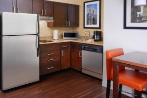 a kitchen with a white refrigerator and a table at Residence Inn by Marriott San Antonio Airport/Alamo Heights in San Antonio