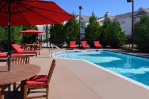a pool with chairs and tables and a red umbrella at Residence Inn by Marriott San Antonio Airport/Alamo Heights in San Antonio