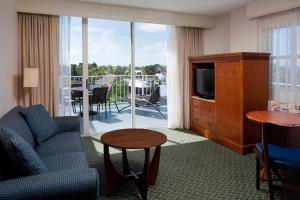a living room with a couch and a television and a balcony at Courtyard by Marriott Key Largo in Key Largo