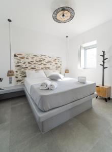 Un dormitorio blanco con una cama grande con toallas. en Santa Marina Syros, en Liaropá