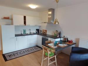 uma cozinha com armários brancos e uma mesa e cadeiras em Apartment Sonne auf Bio-Hof em Merano
