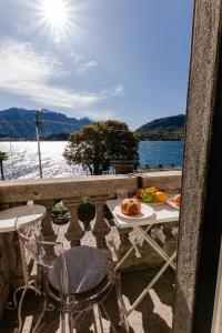 una mesa y sillas en un balcón con vistas al agua en Bella Belle Griante, en Cadenabbia