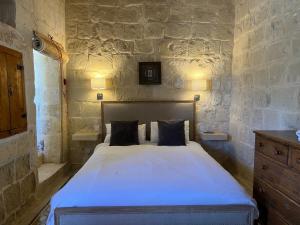 een slaapkamer met een bed in een stenen muur bij Razzett Ghasri in Għasri