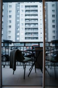 a table and chair on a balcony with buildings at Smiling Apartment in Cluj-Napoca