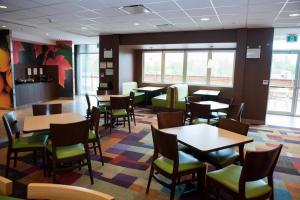 Fairfield Inn & Suites by Marriott Moncton في مونكتون: غرفة طعام مع طاولات وكراسي ونوافذ