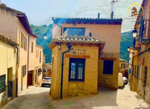 un petit bâtiment jaune dans une rue d'une ville dans l'établissement Casa de la GALERA, à Tolède