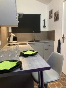 een keuken met een tafel met 2 stoelen en een wastafel bij Studio avec terrasse et parking au Mans in Le Mans