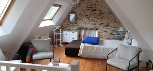ein Schlafzimmer mit einem Bett und einem Stuhl im Dachgeschoss in der Unterkunft La Glycine in Landévant