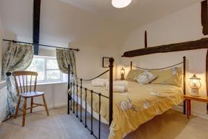 a bedroom with a bed and a chair and a window at Lavender Cottage in Stiffkey