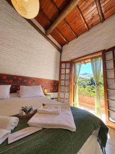 um quarto com uma cama e uma grande janela em Hotel Ponto de Luz em Joanópolis