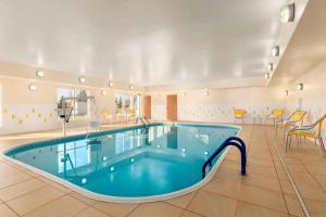 Una piscina en una habitación grande con sillas y mesas. en Fairfield Inn & Suites Saginaw, en Saginaw