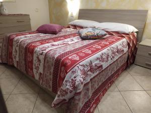 a bed with a red and white blanket and pillows on it at Casa Maria in Portoferraio