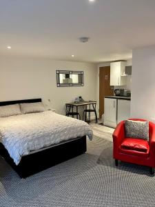 a bedroom with a bed and a red chair at Basement Studio by the Bay in Morecambe