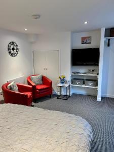 a bedroom with two red chairs and a flat screen tv at Basement Studio by the Bay in Morecambe