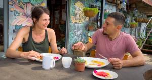 mężczyzna i kobieta siedzący przy stole jedzący jedzenie w obiekcie Casa Tranquilo Hostel w mieście Monteverde