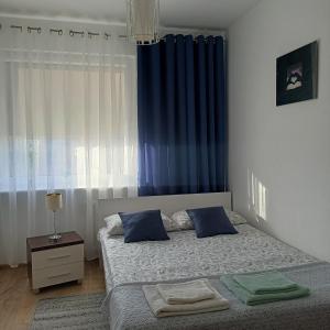 a bedroom with a bed and a blue curtain at Pomaranczowa Apartment in Szczecin