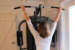 Una mujer en una máquina de gimnasio con sus brazos en el aire en Barlis - stilvolle Ferien in typischem Dorfhaus, en Alpnach