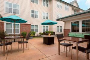 un patio con 2 mesas y sillas con sombrillas azules en Residence Inn by Marriott Houston The Woodlands/Lake Front Circle en The Woodlands